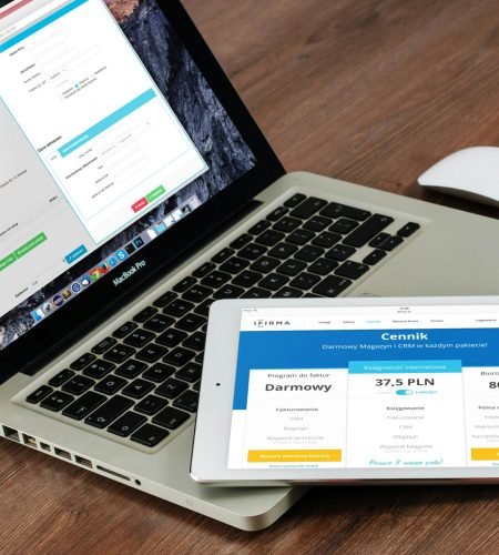Close-up of a laptop and tablet on a wooden desk, showcasing modern technology.